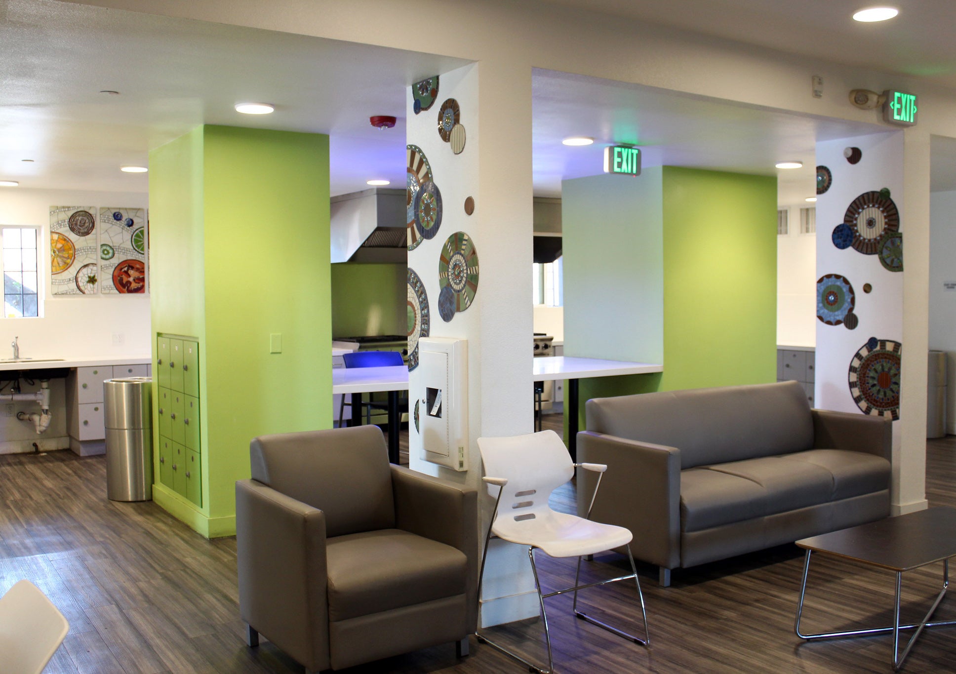 An apartment lobby with green walls, couches, and white pillars filled with circular mosaics.