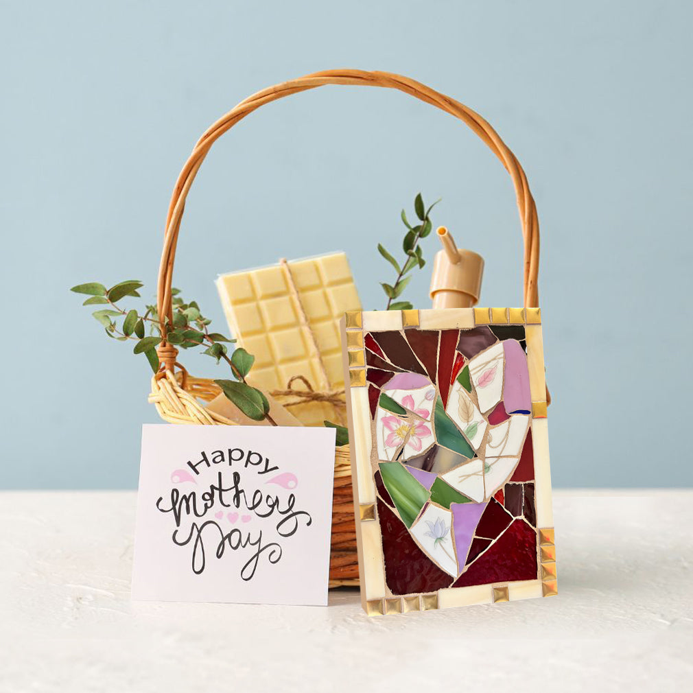 A basket of gift for mother's day, including soap, a card, and a mosaic of a heart.