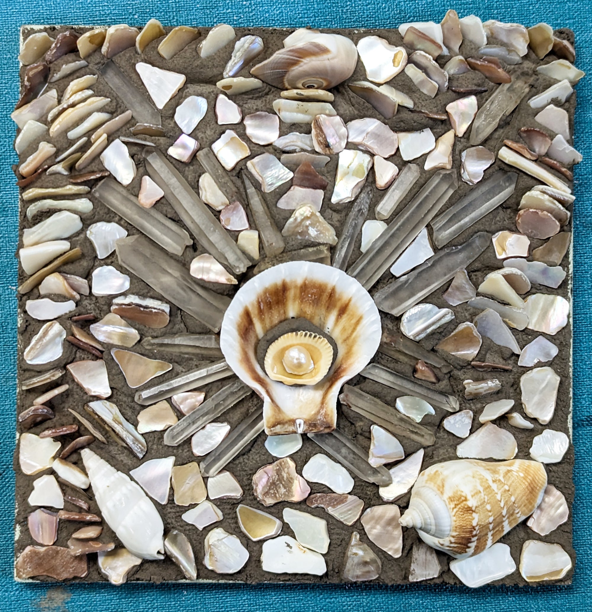 Mosaic made of shells and other found material on a blue background.