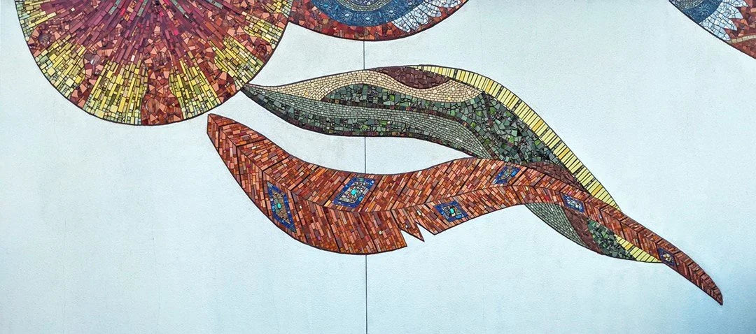 Large mosaic feathers made of warm colored tiles.