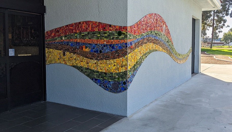 A large wavy rainbow mosaic going around the corner of a wall.