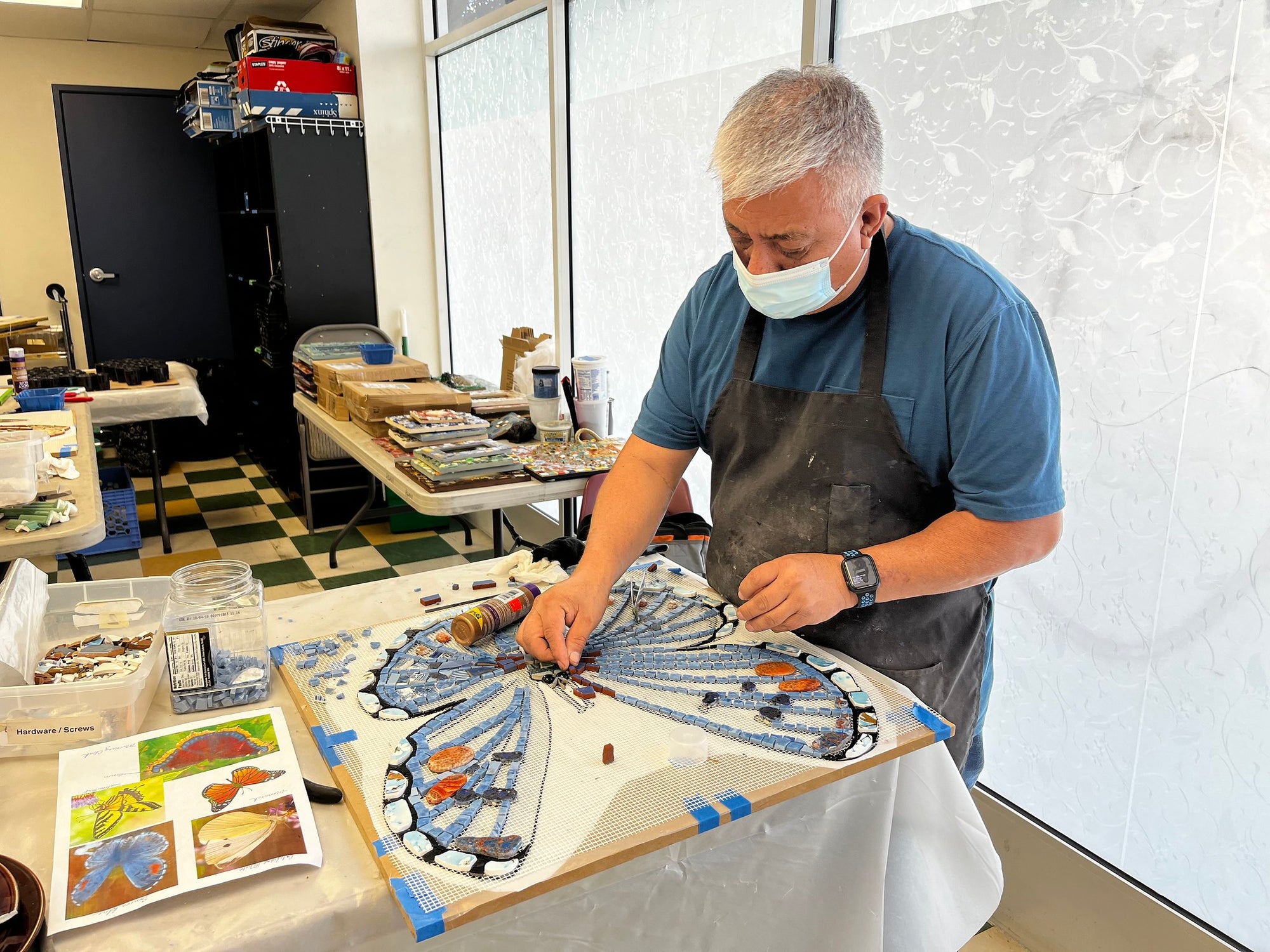 Piece by Piece artist putting together mosaic pieces to create a blue butterfly