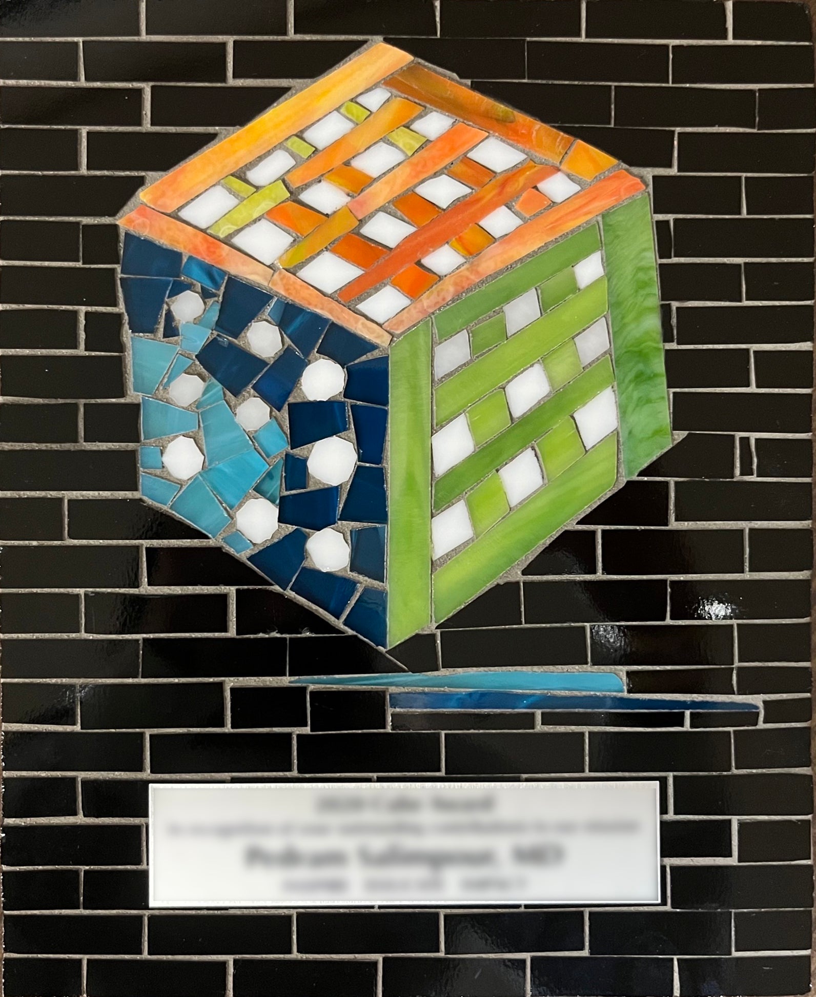 Discovery Cube Award with black background and mosaic cube of orange, blue, and green